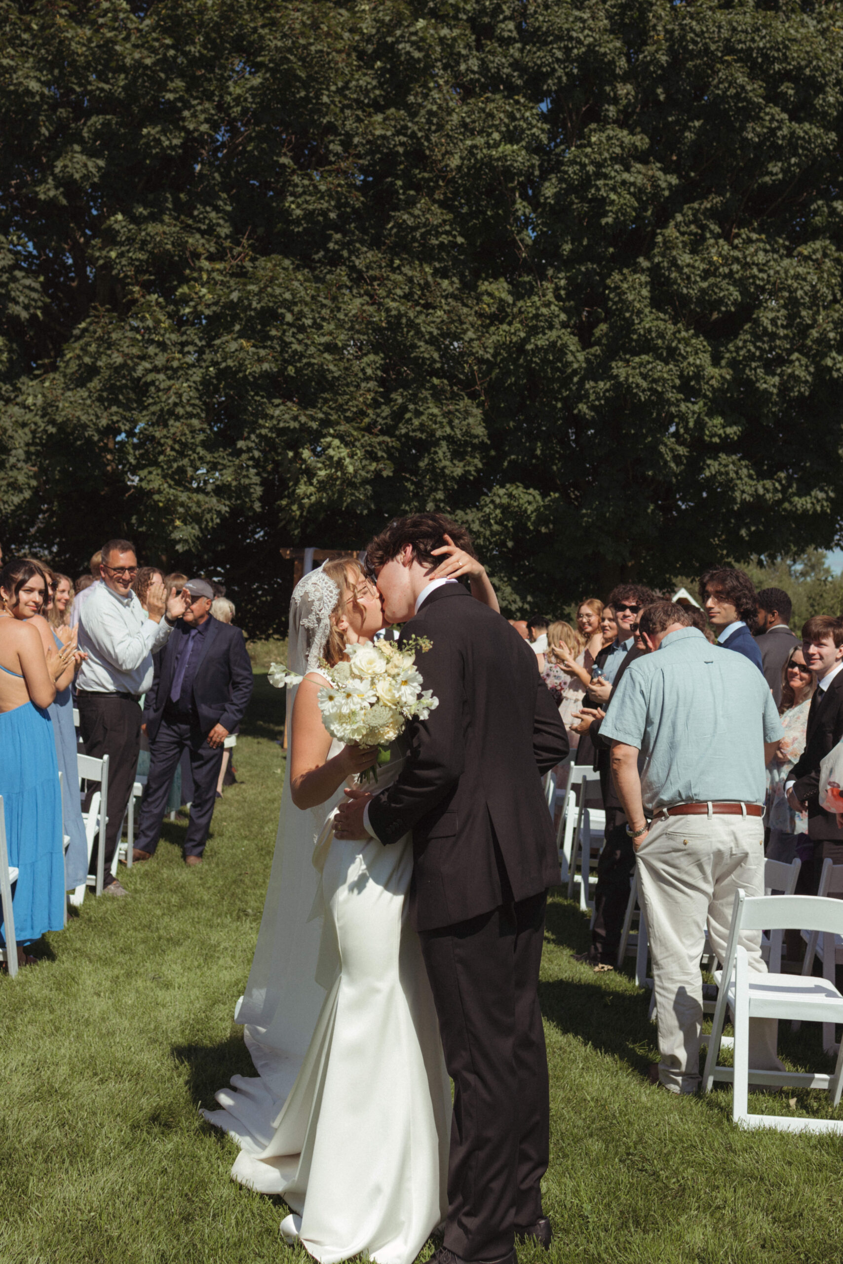mid aisle kiss as bride and groom walk down after outdoor ceremony 