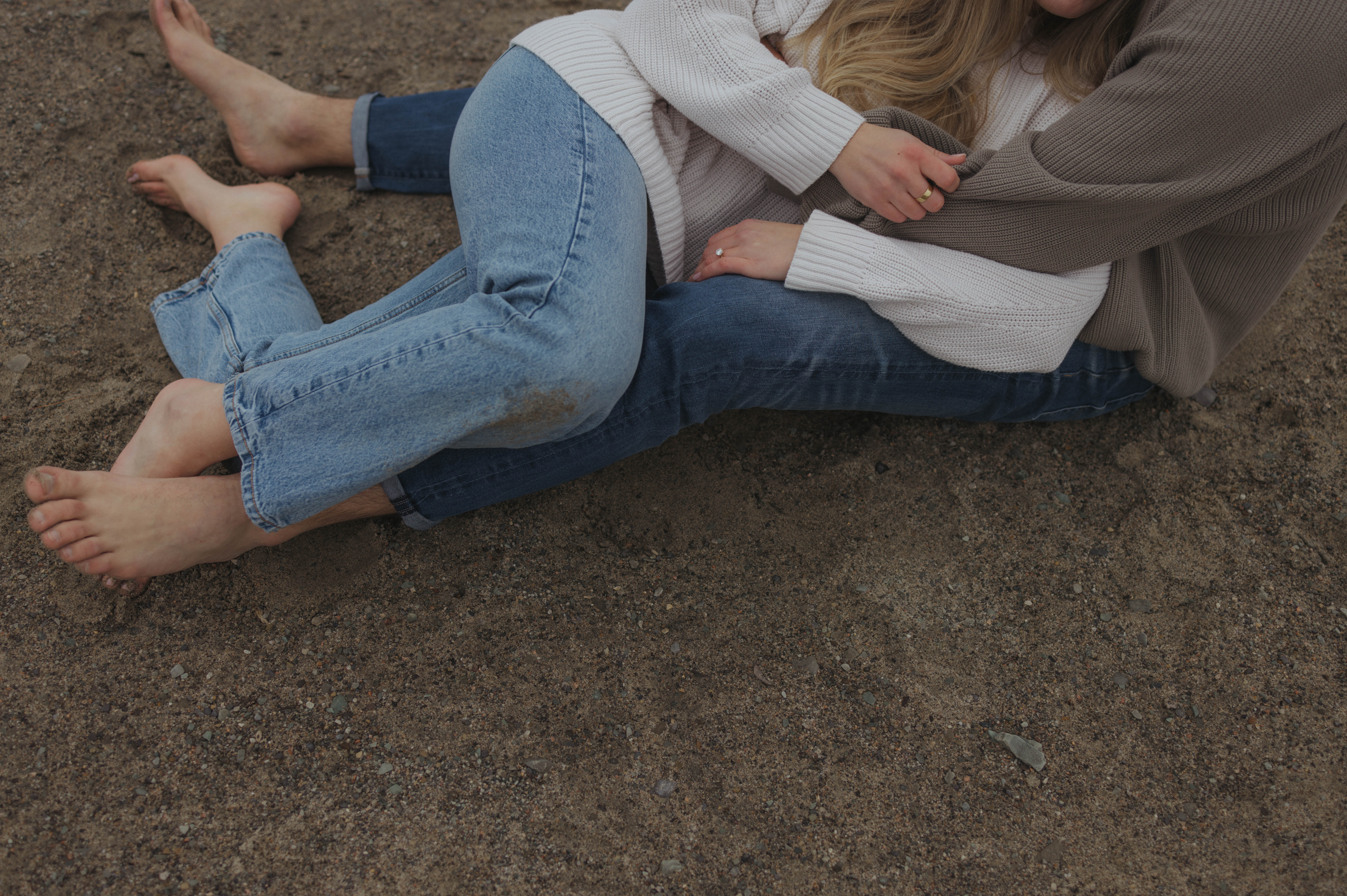 couple cuddling on beach barefoot during early spring engagement session in Ottawa 