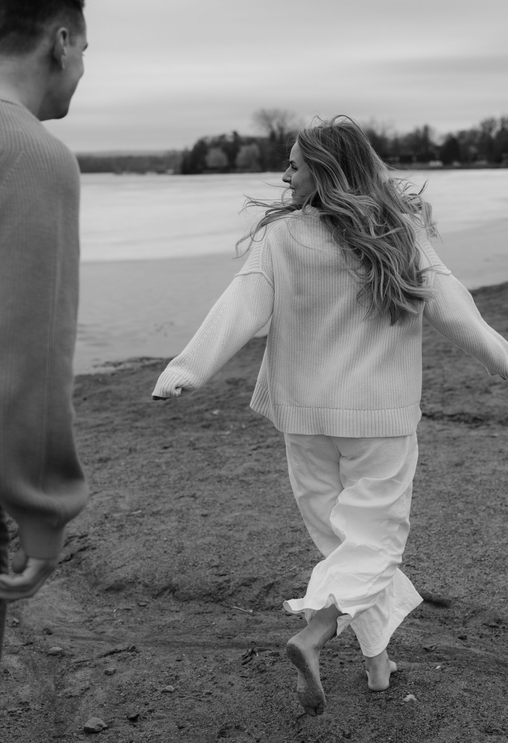 running in linens and knits on the beach during their engagement session