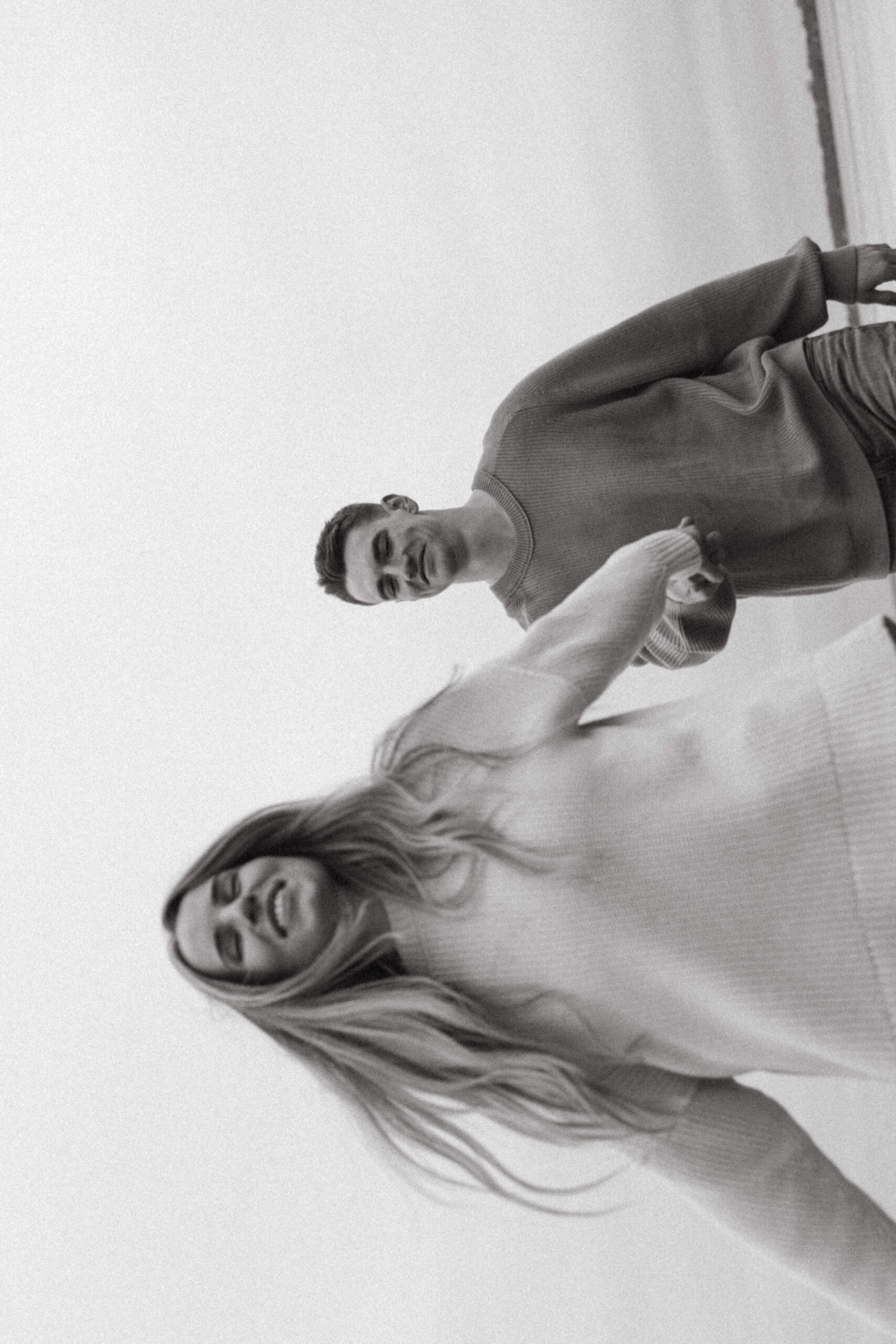 couple laughing and walking on beach during engagement session