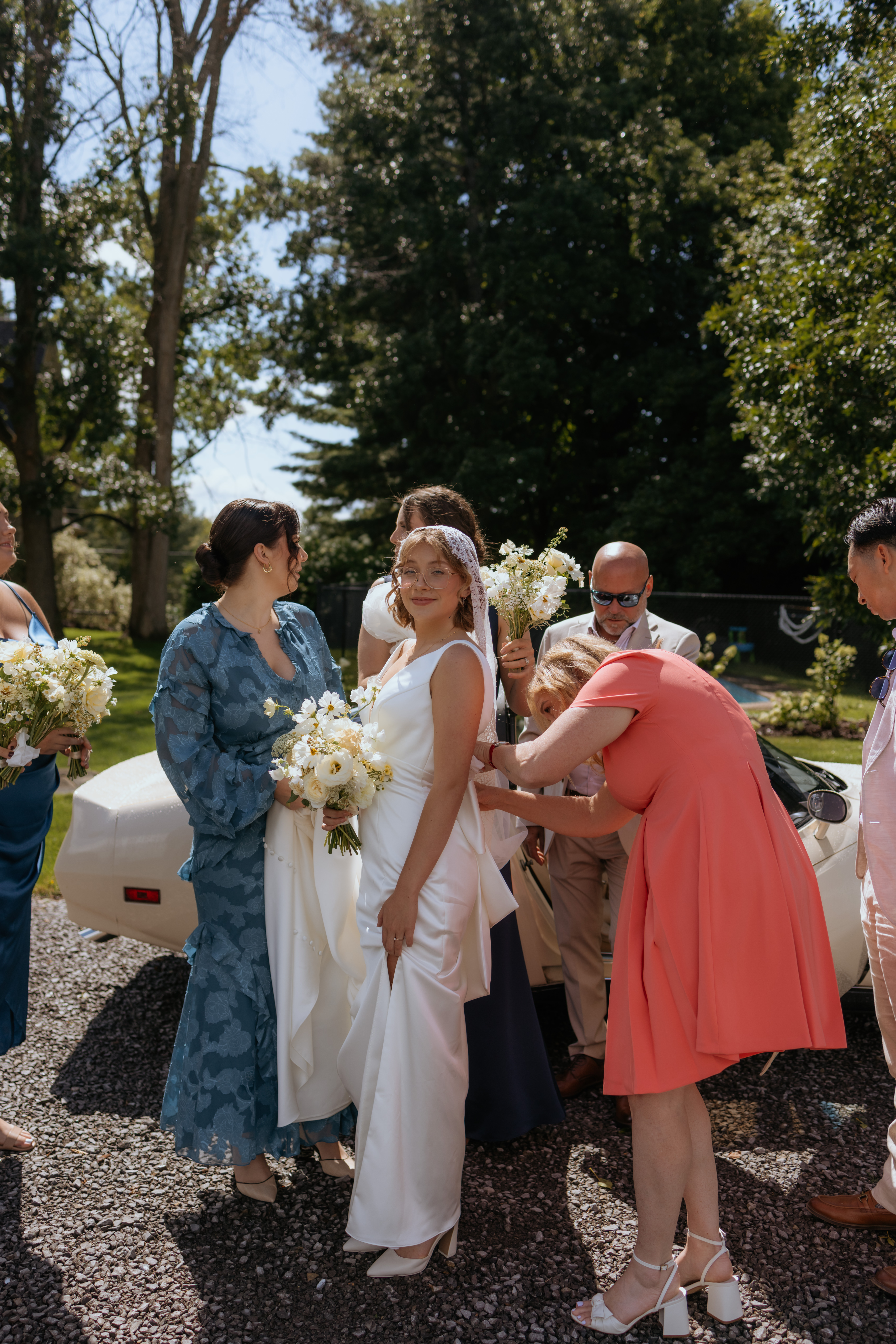 mother of the bride fixing the brides dress before she walks down the aisle in outdoor ceremony