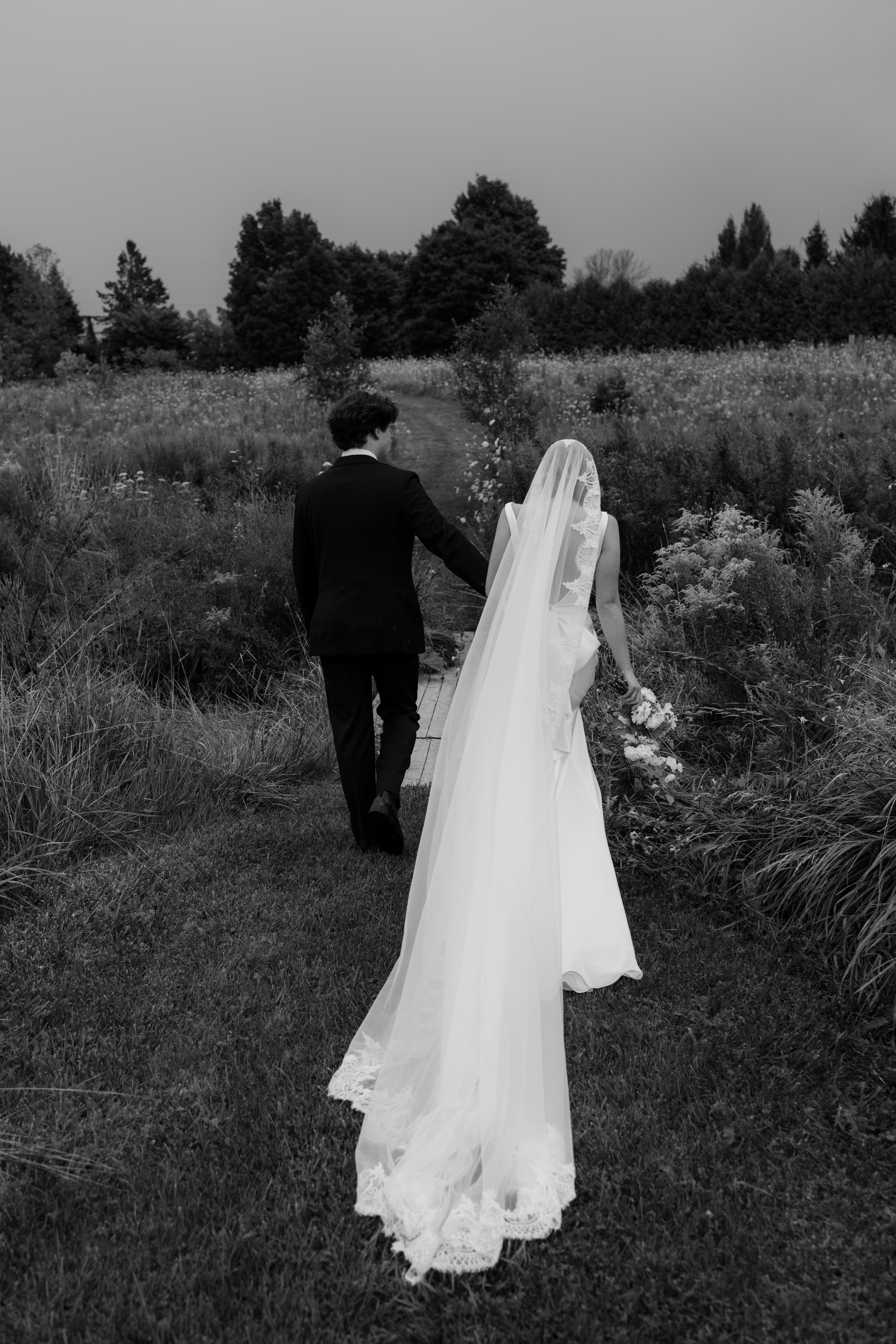 bride and groom walk into field after outdoor ceremony 