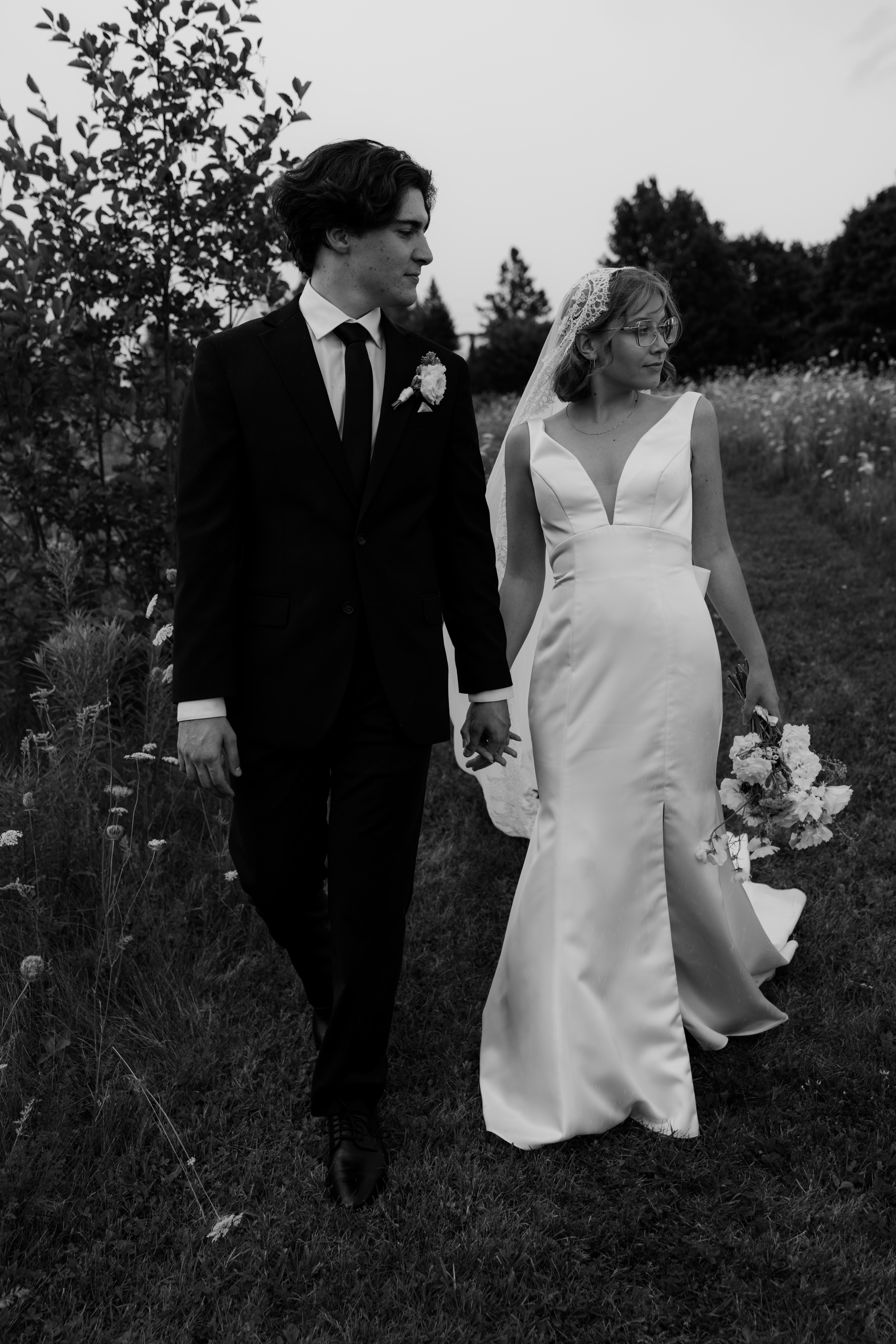 bride and groom looking over shoulder as they walk toward their photographer at ottawa wedding