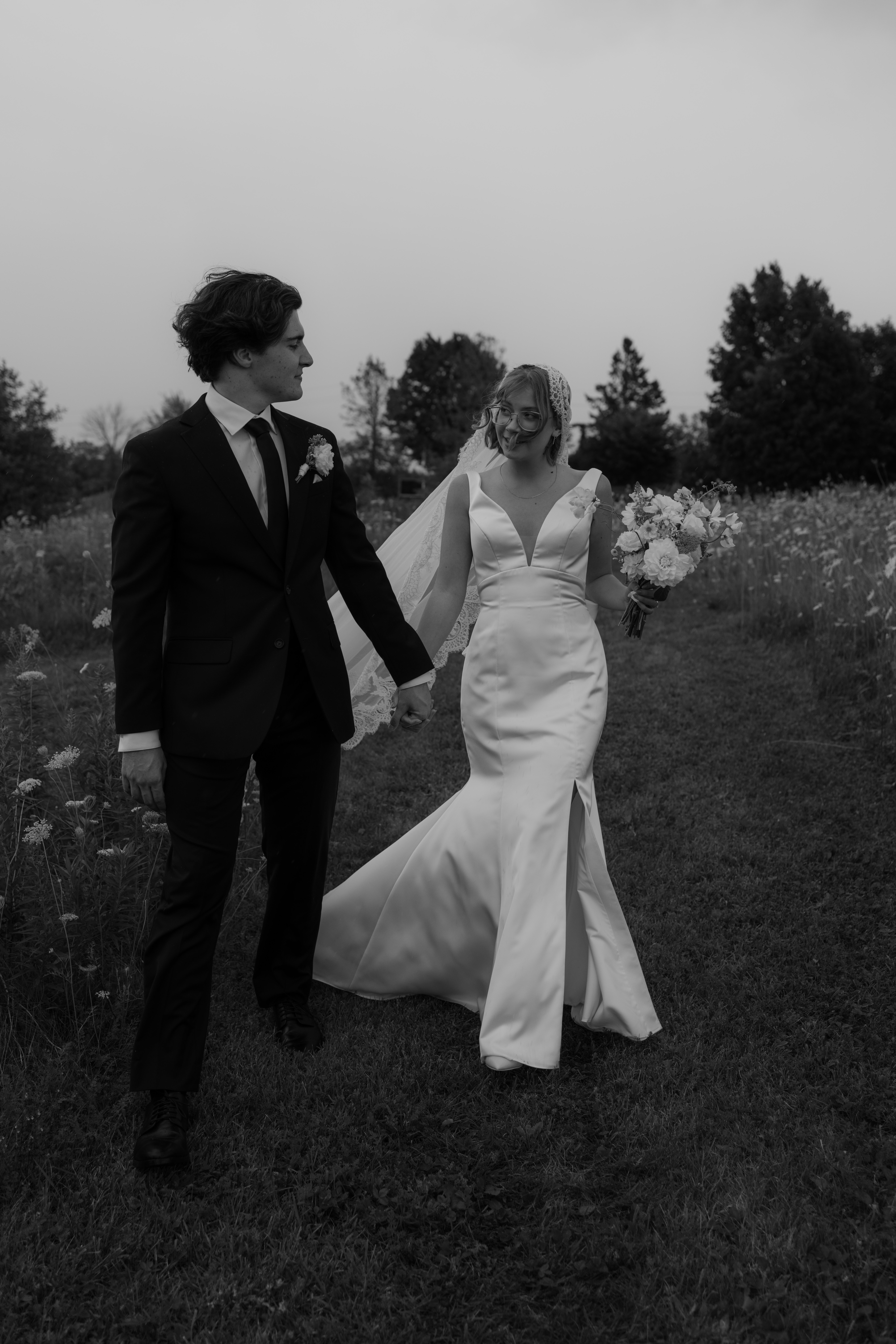 bride and groom laughing as they walk toward wedding phototgrapher
