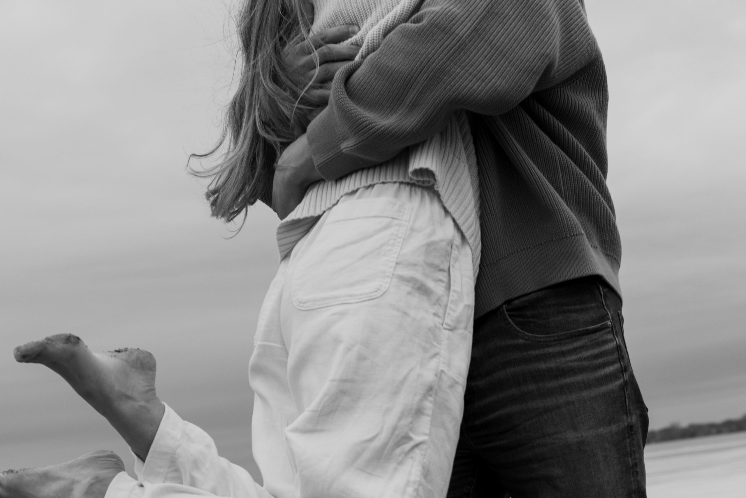 couple spinning on a beach during their barefoot engagment session