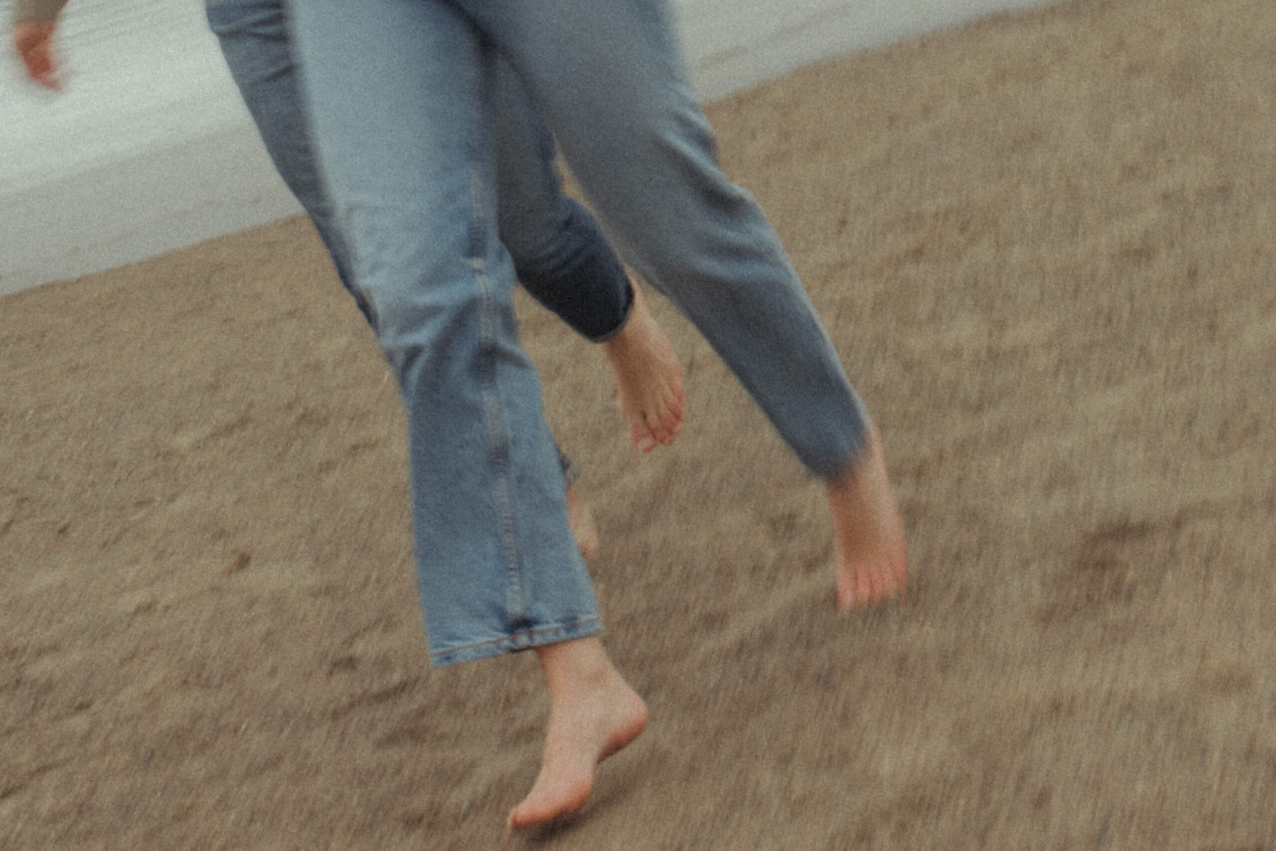 couple running barefoot on the beach during their engagement session