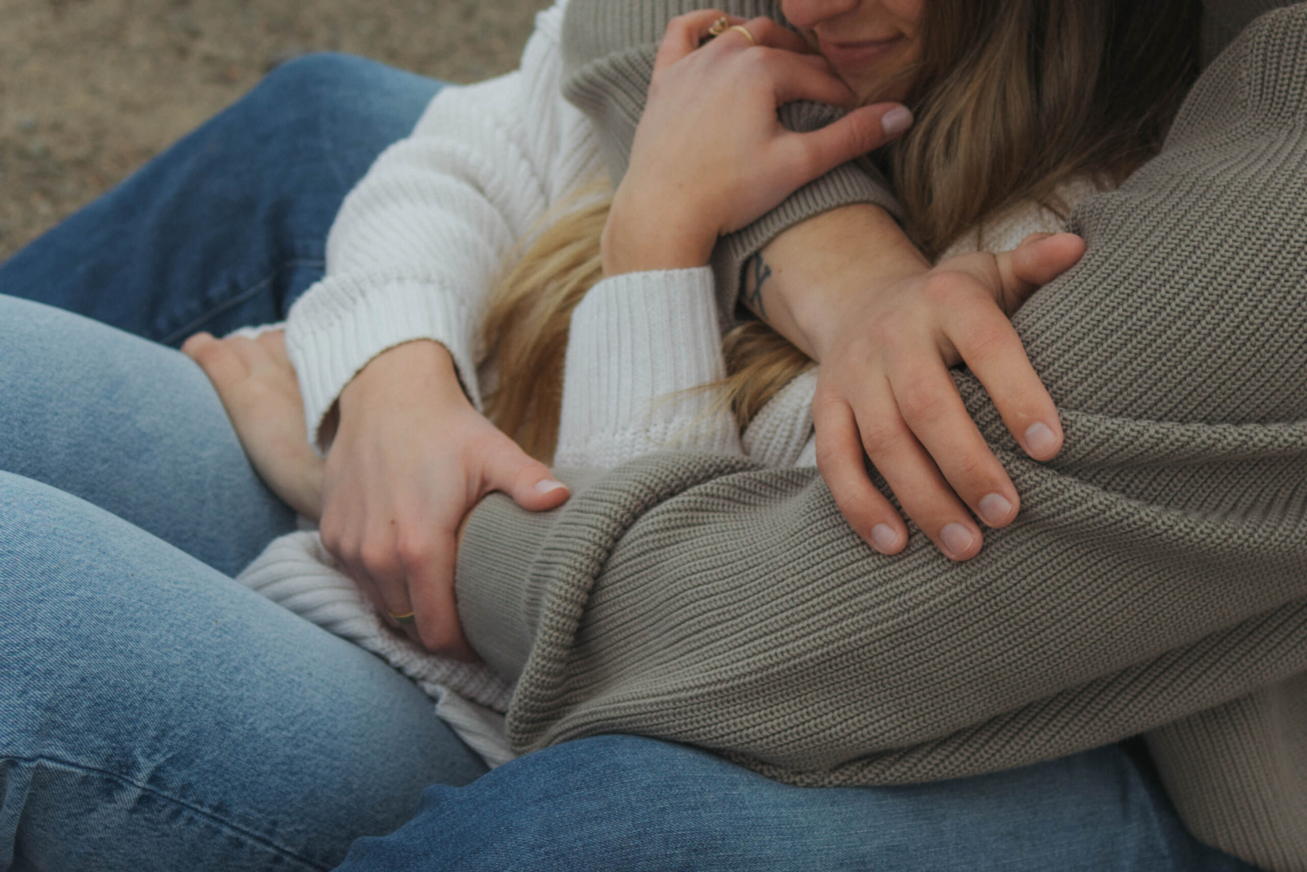 couple cuddled up on the beach in knits during their engagement session