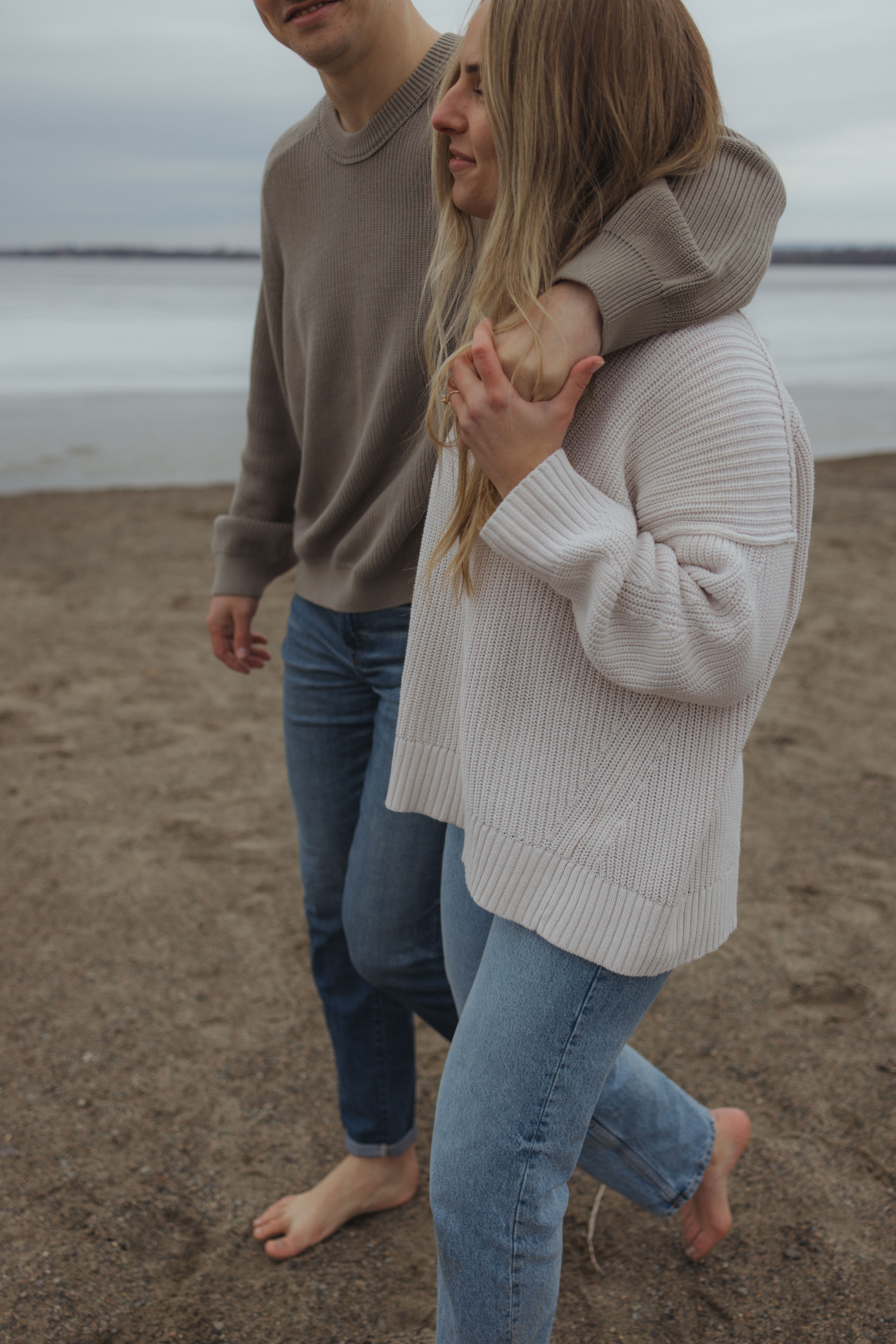 arm wrapped around should as couple walks the beach during engagement session