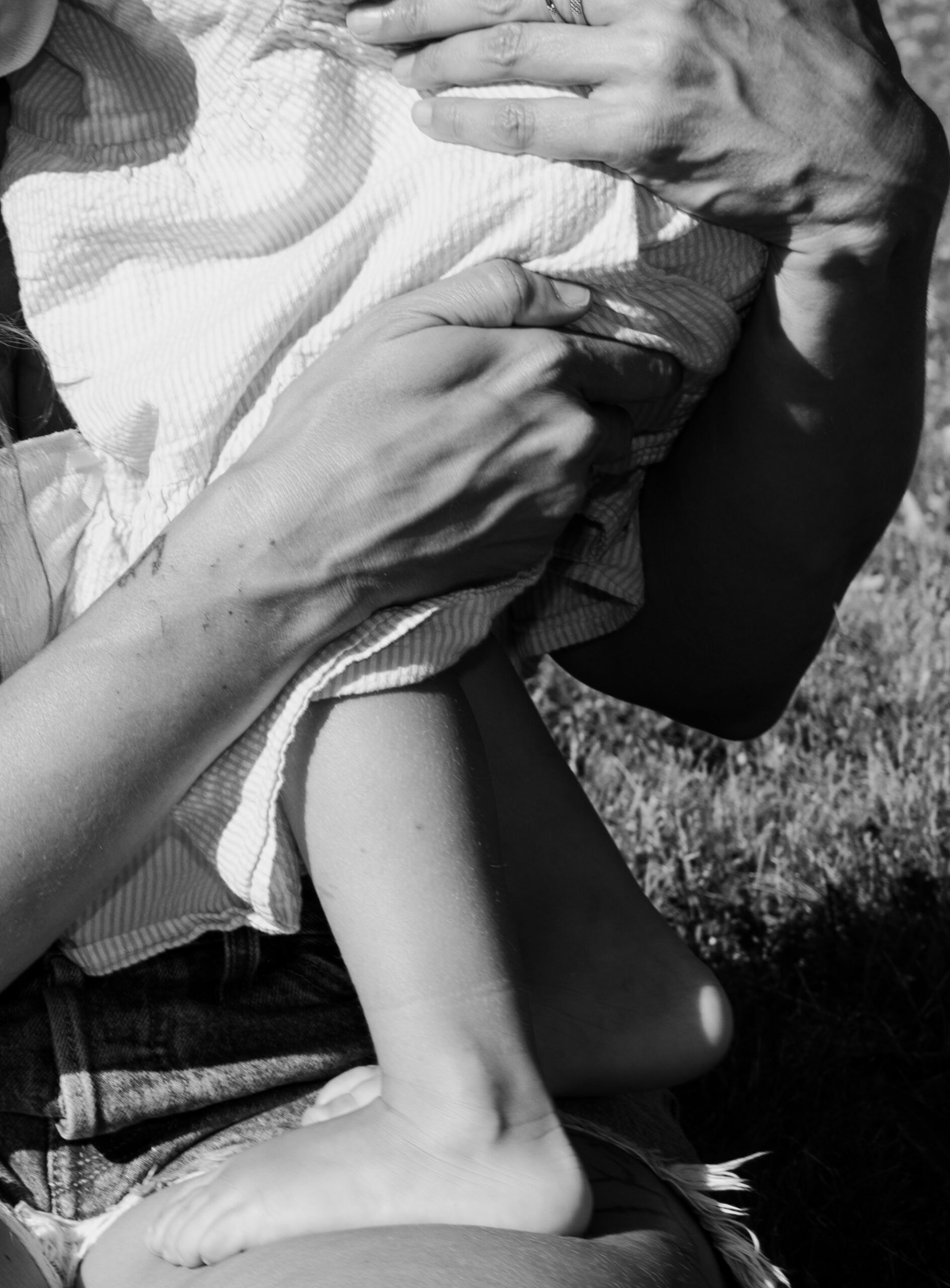 child standing on mothers leg in the garden 