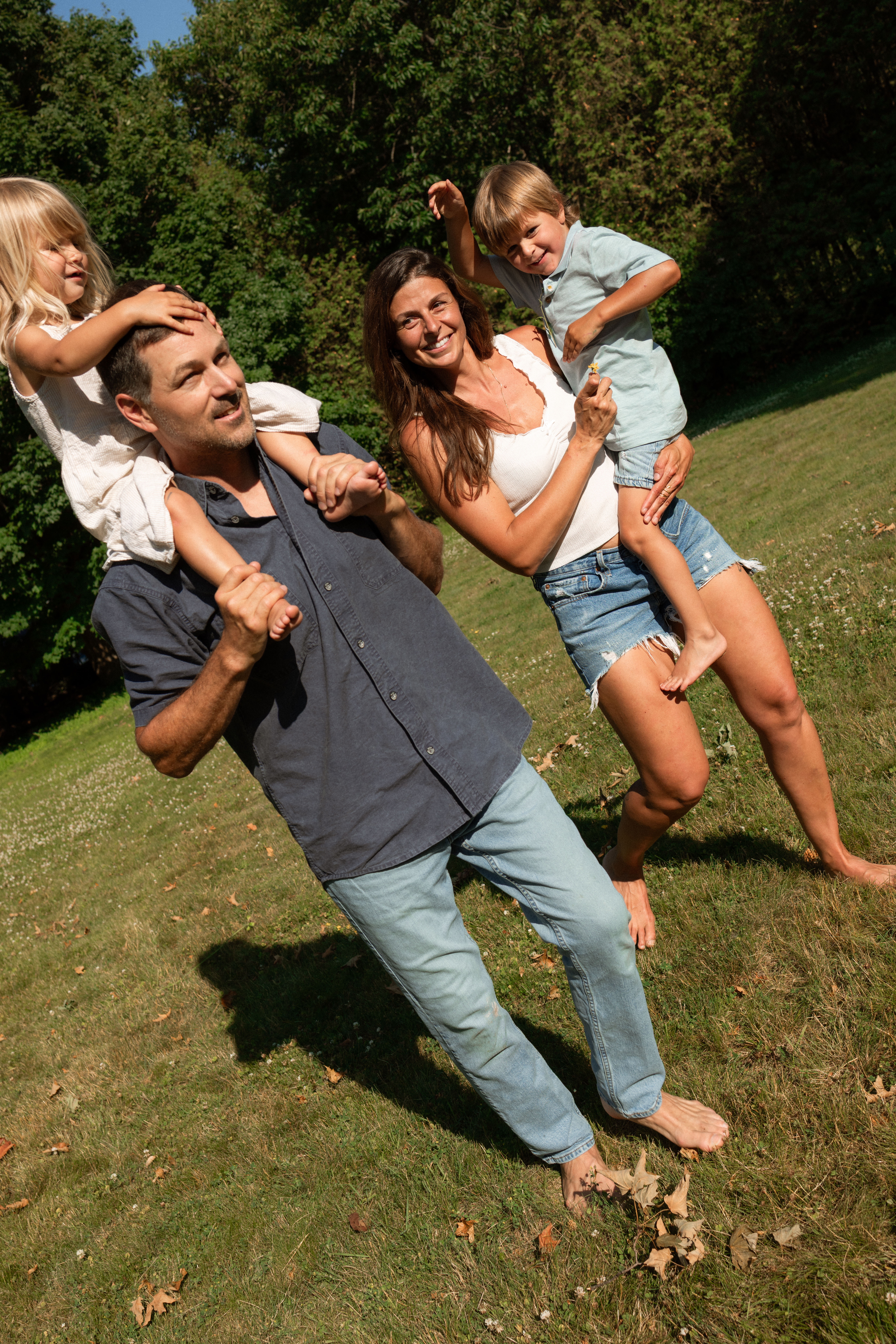 family of four is all smiles as they play and explore backyard during documentary session with top family photographer