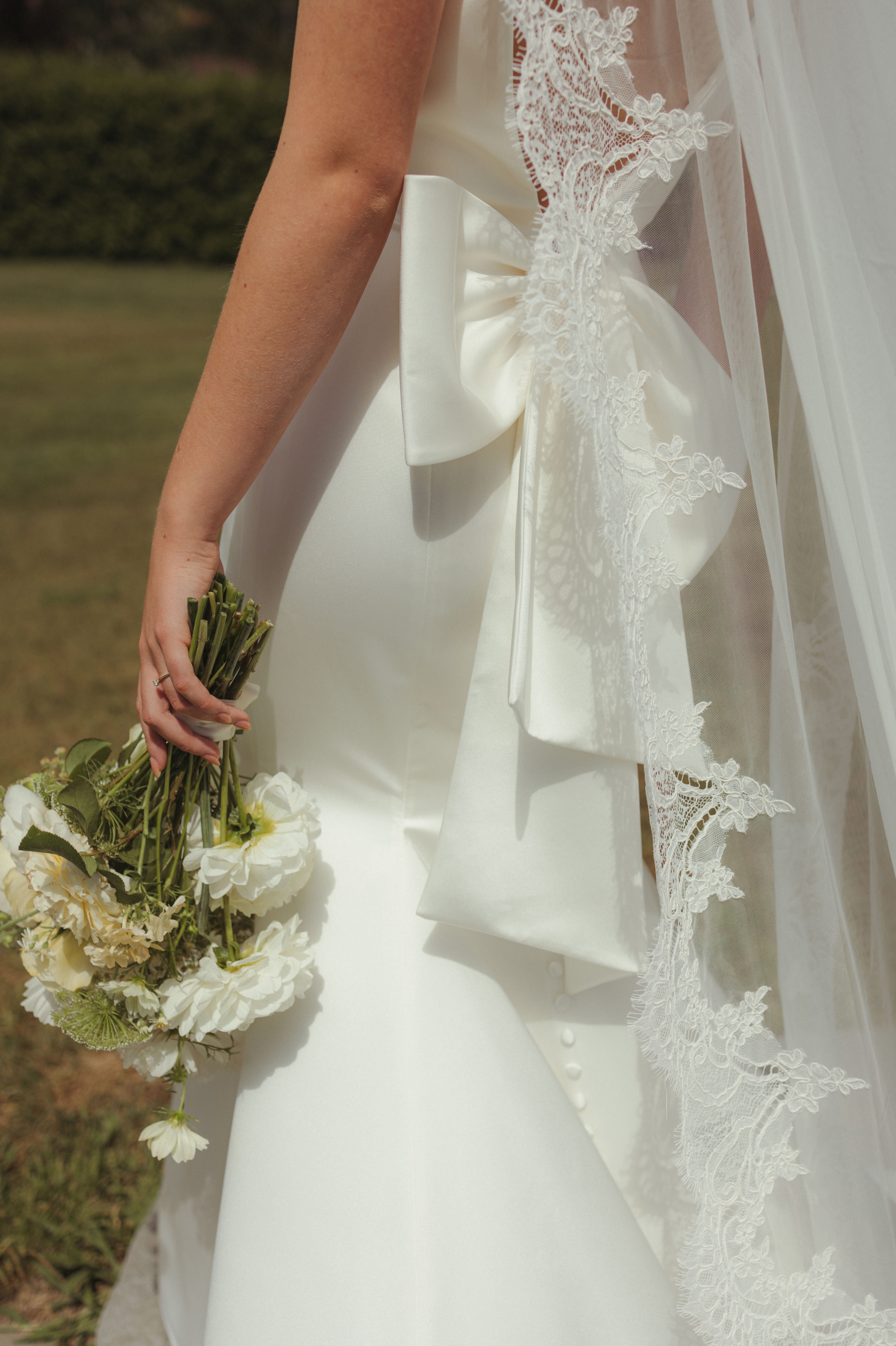 candid bride portrait from chic outdoor editorial wedding of bride in silk gown with huge statement bow on the back