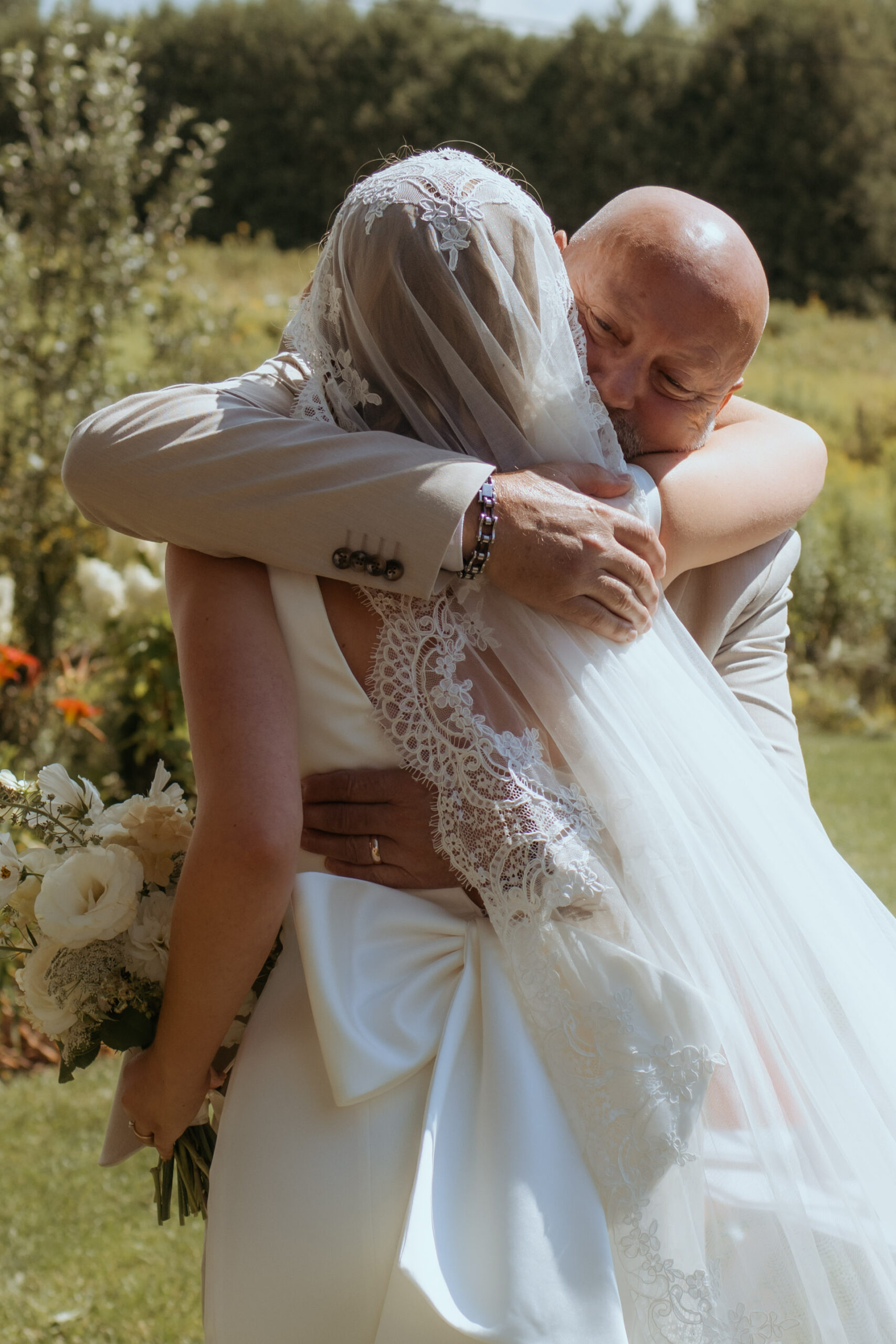 father and daughter hug at outdoor summer ceremony wedding