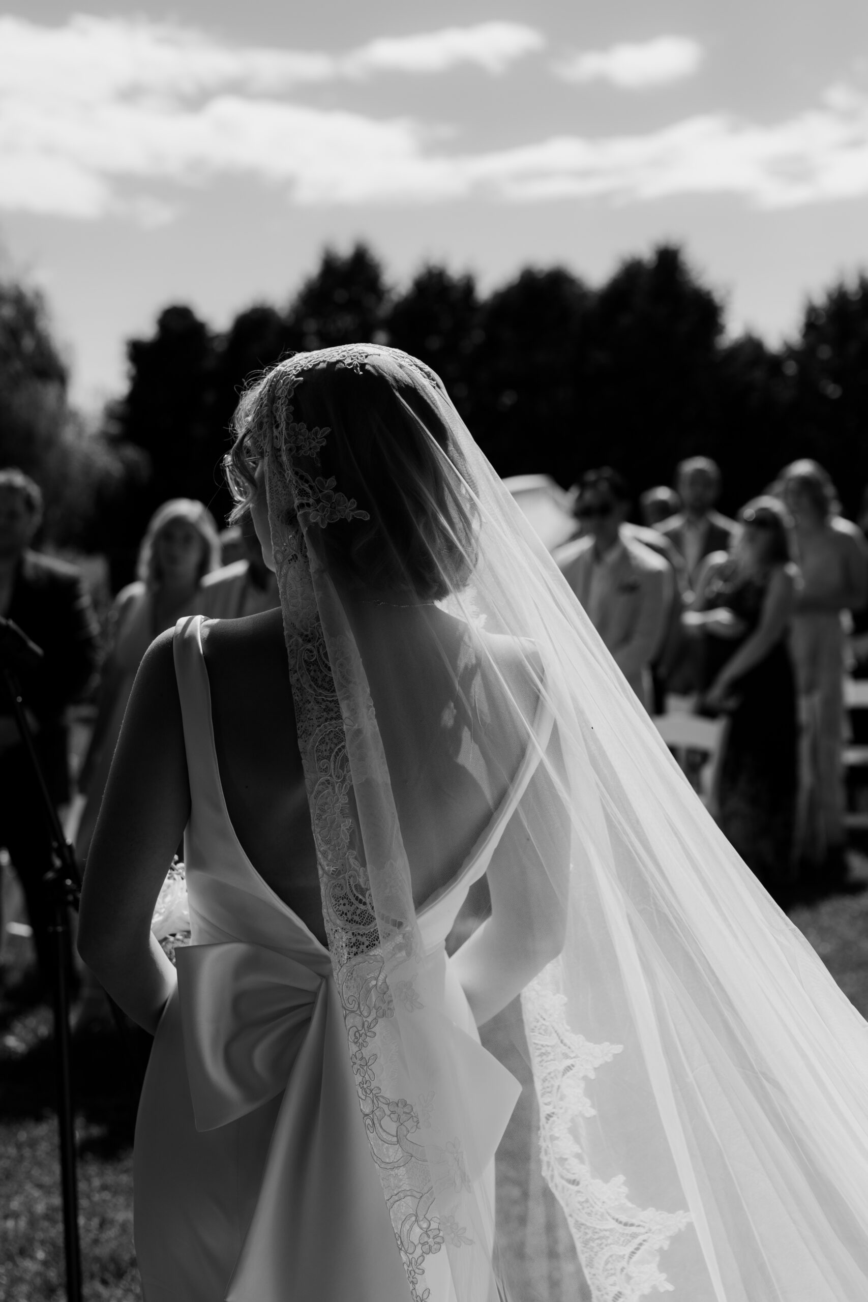 veil in wind as beautiful bride is at the alter during summer ceremony