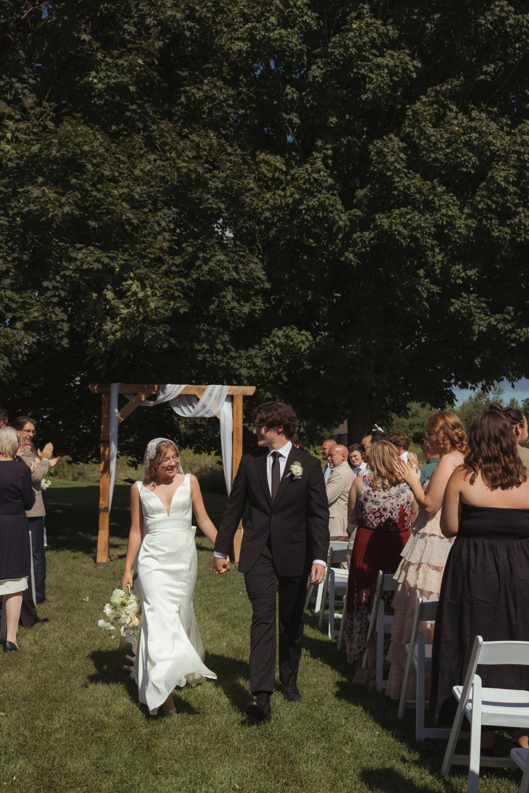 bride and groom walk down aisle during chic outdoor summer ceremony in ottawa