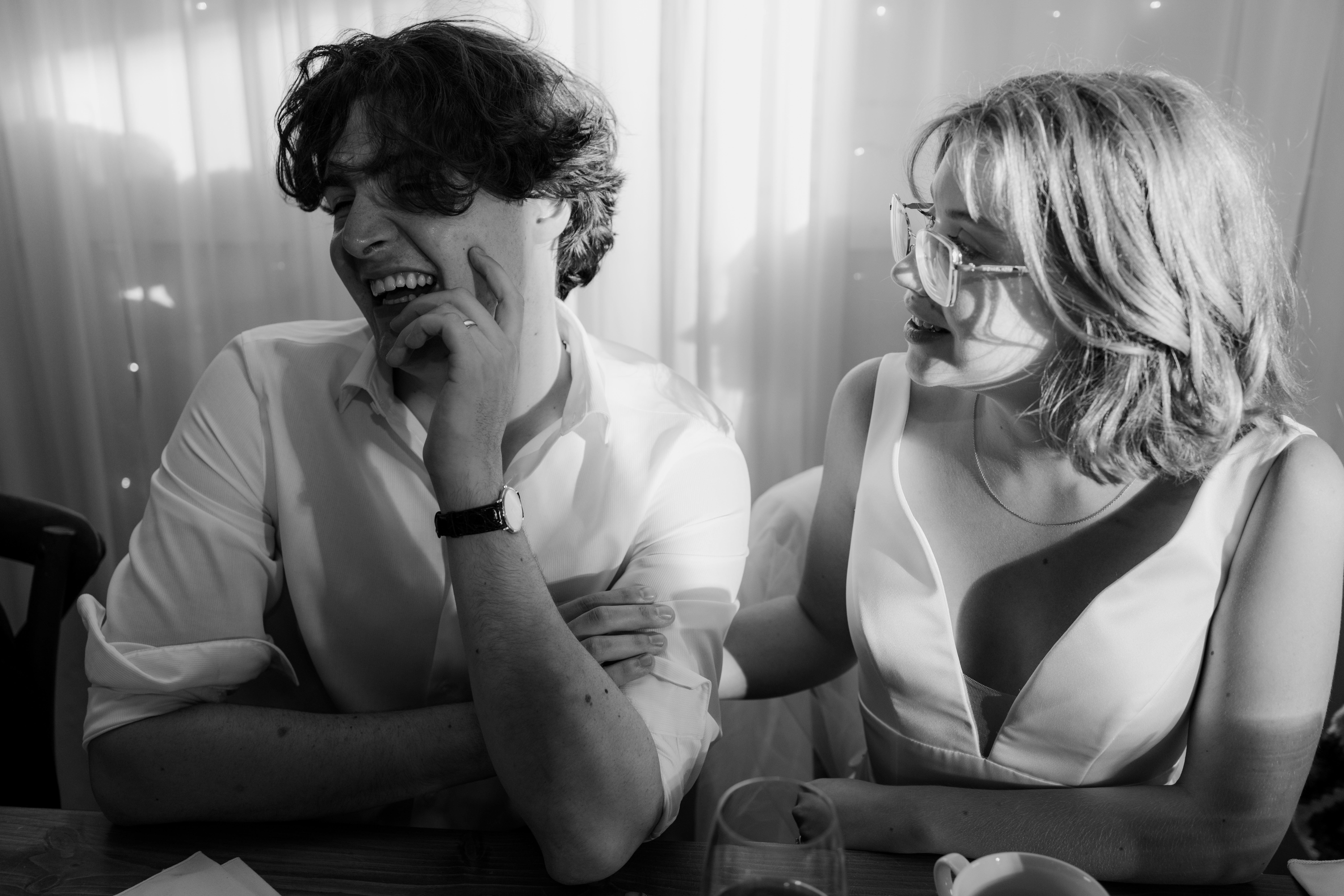 bride and groom at head table smiling during their reception while love ones have speeches 