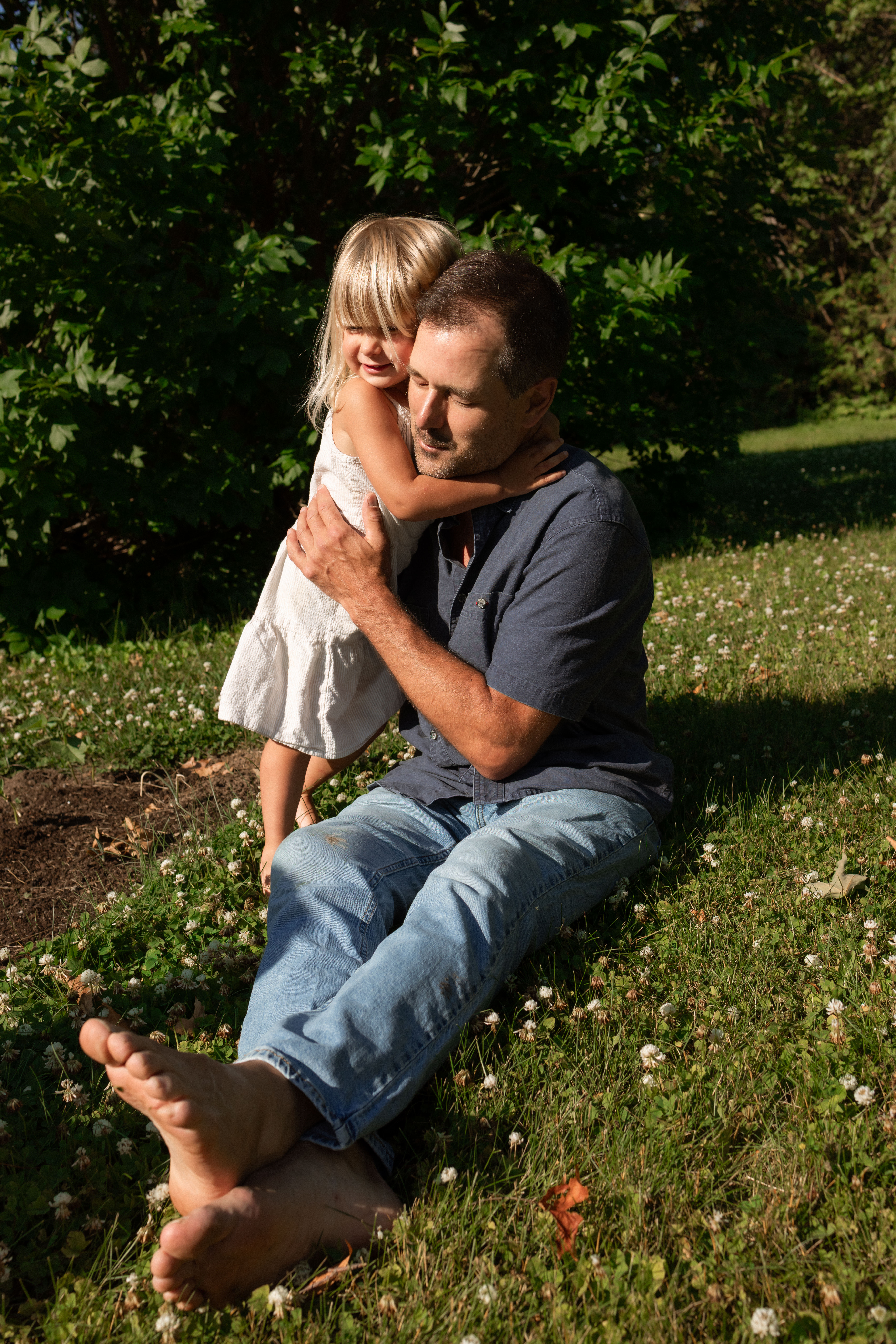 father and daughter hugging in the sunlight during backyard family session shot by Ottawa Family Photographer