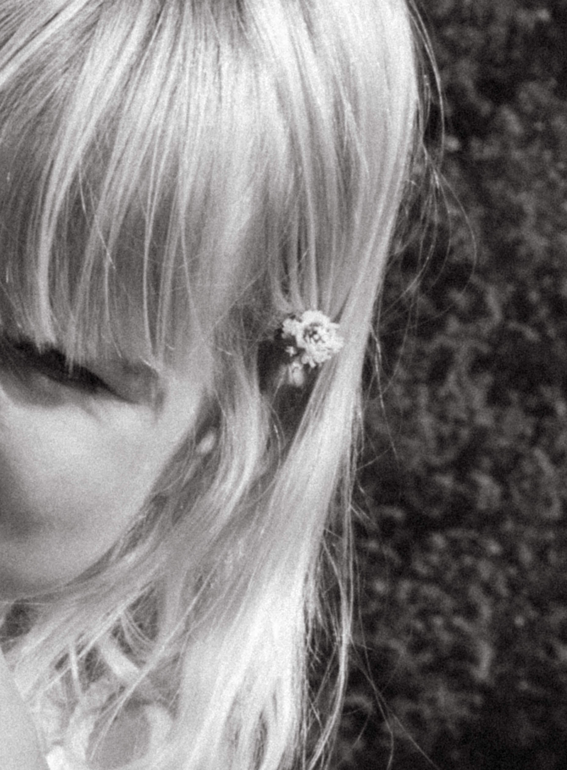a beautiful moment captured of a tiny flower placed in daughters hair from their garden 