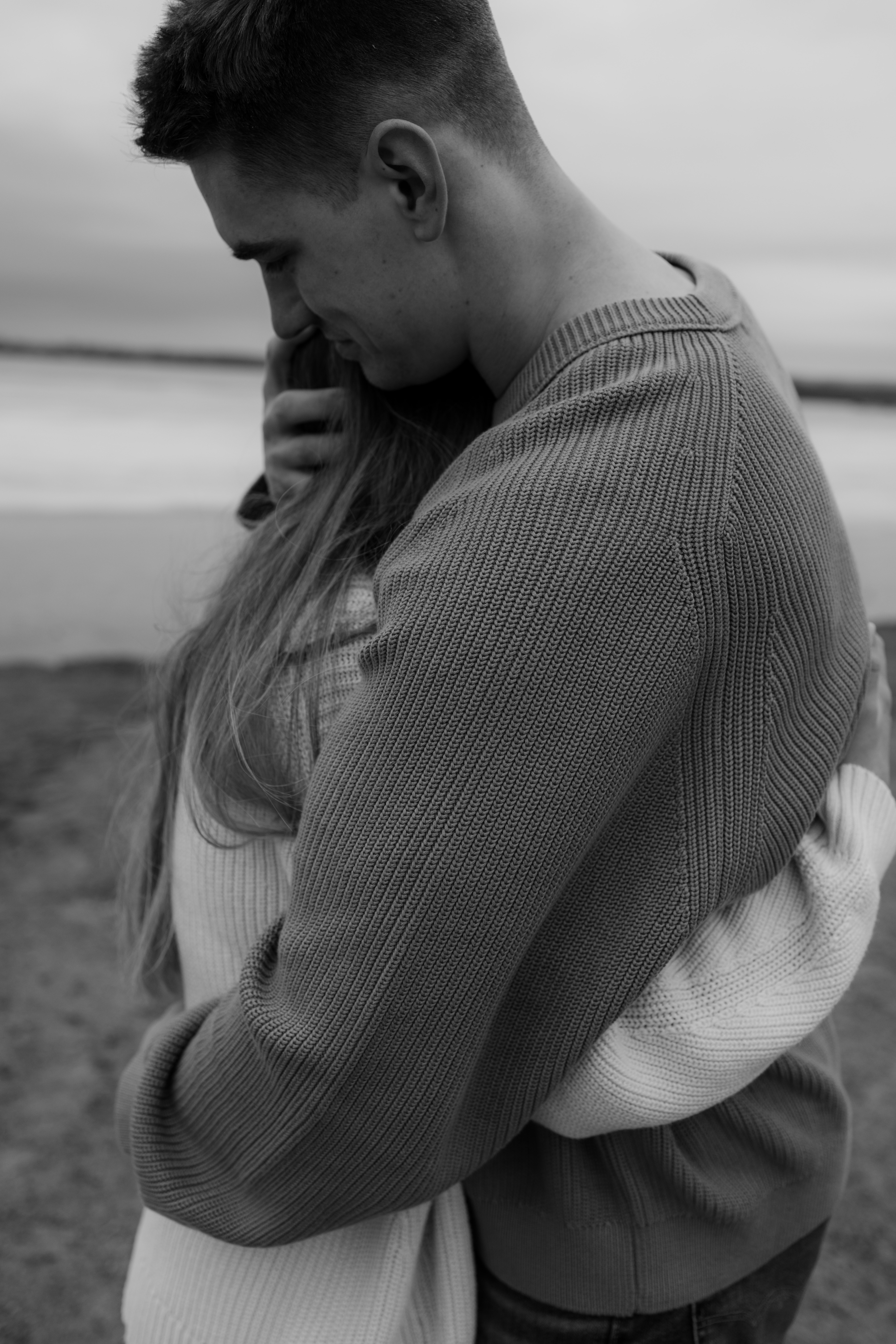 hugging in their knits on the beach