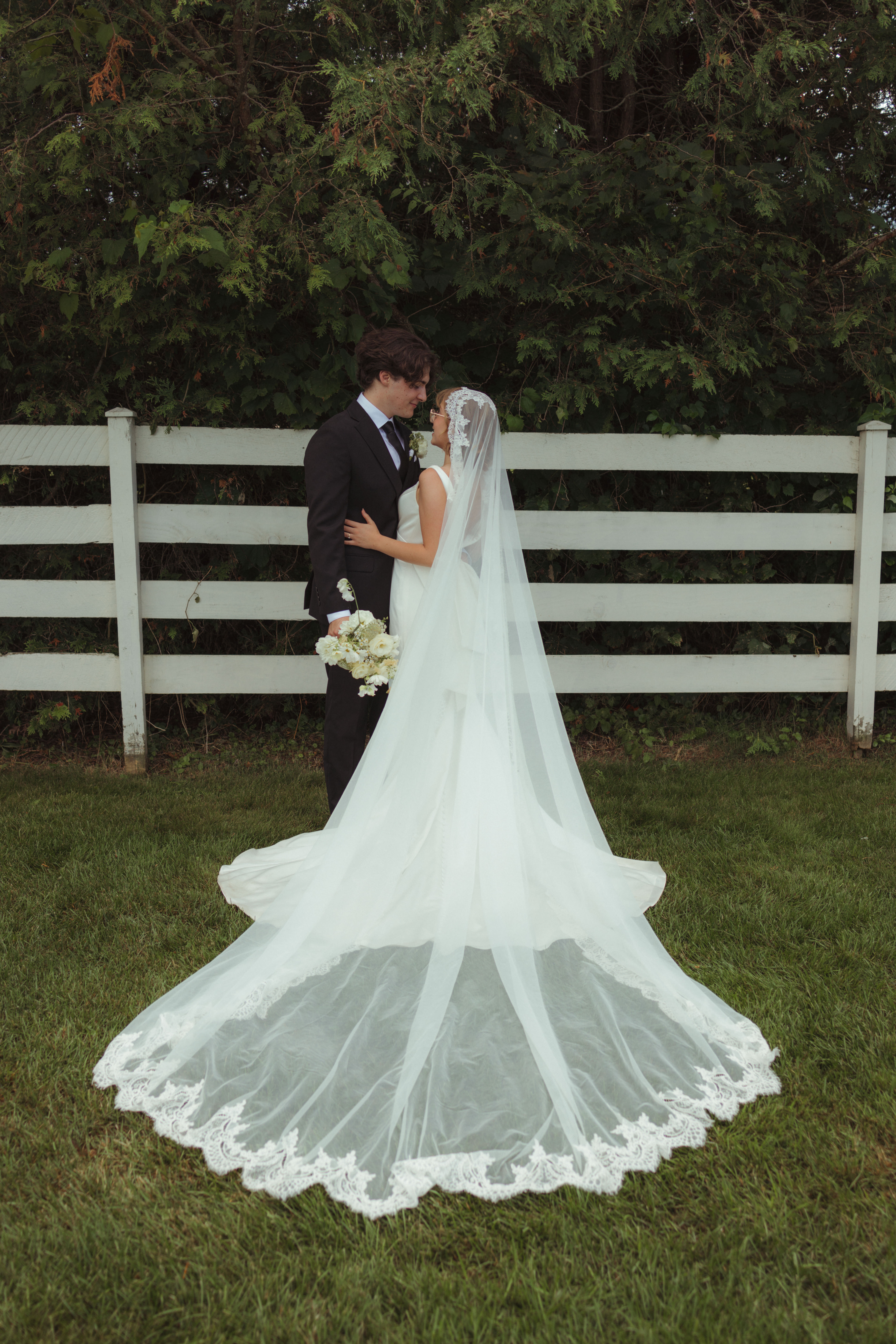 bride and groom have an editorial pose in front of gorgeous fence at outdoor wedding venue