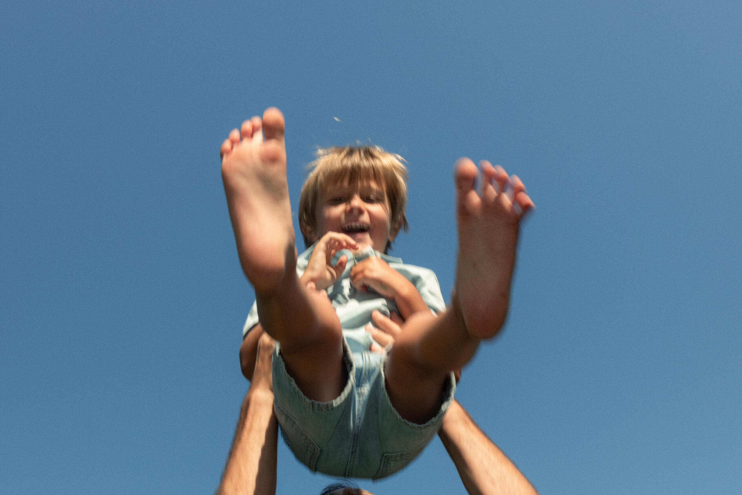 candid noment of little boy flying in the air with his dad's arms around him- shot by Ottawa family photographer 