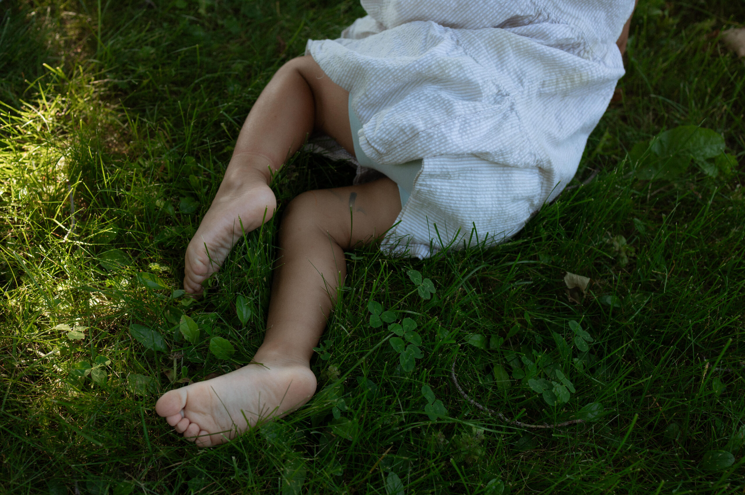 candid moment of child laying in her backyard picking flowers 