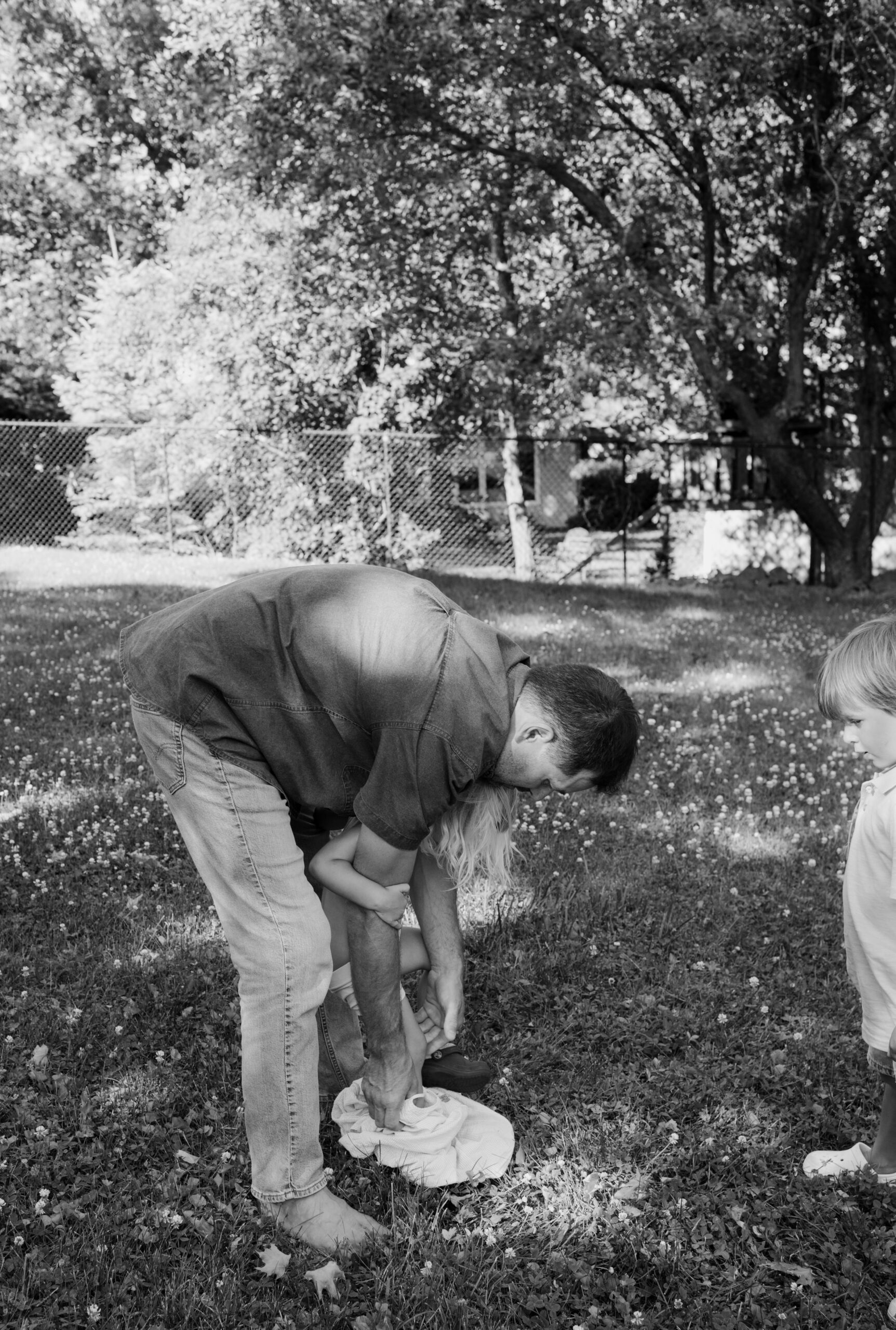 candid moment between dad and children in their backyard of farmhouse in Ottawa ON