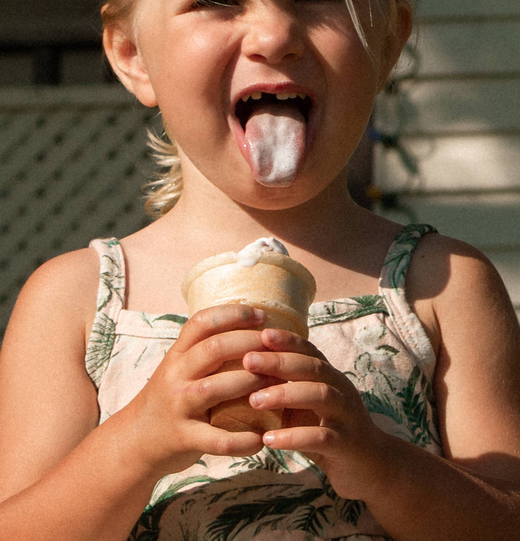 candid moment of children in their yard eating their ice cream cones during authentic summer family session 