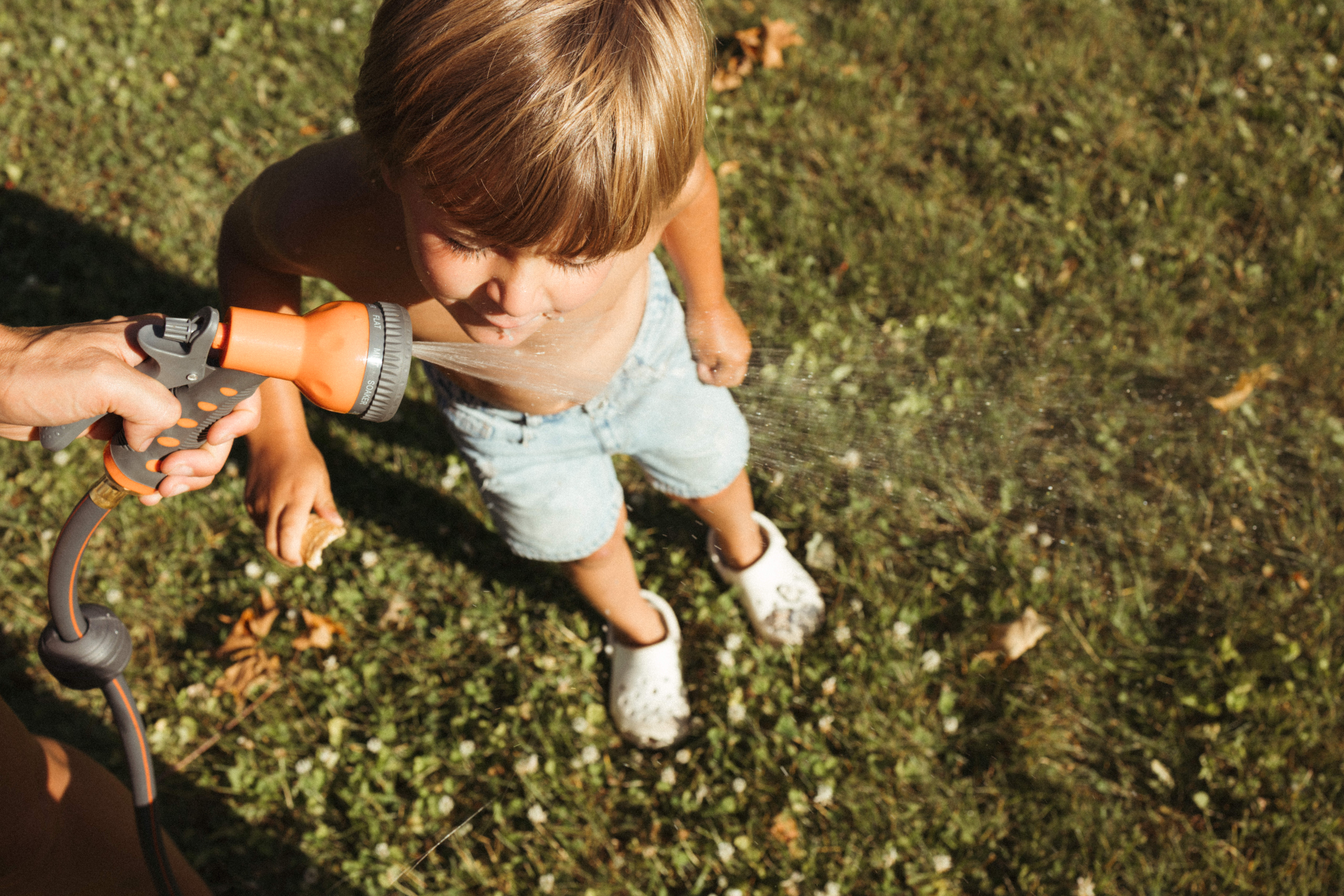 kids drinking from garden hose during backyard summer family session