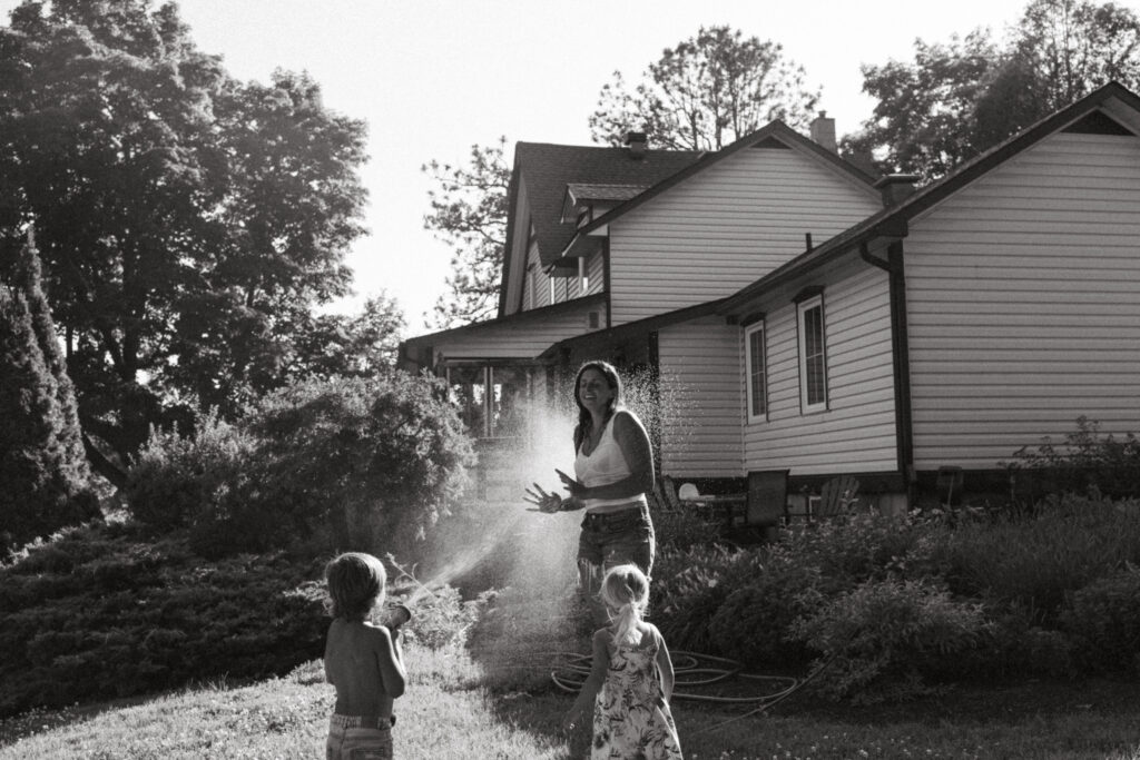 mother plays with children behind their beautiful farmhouse 