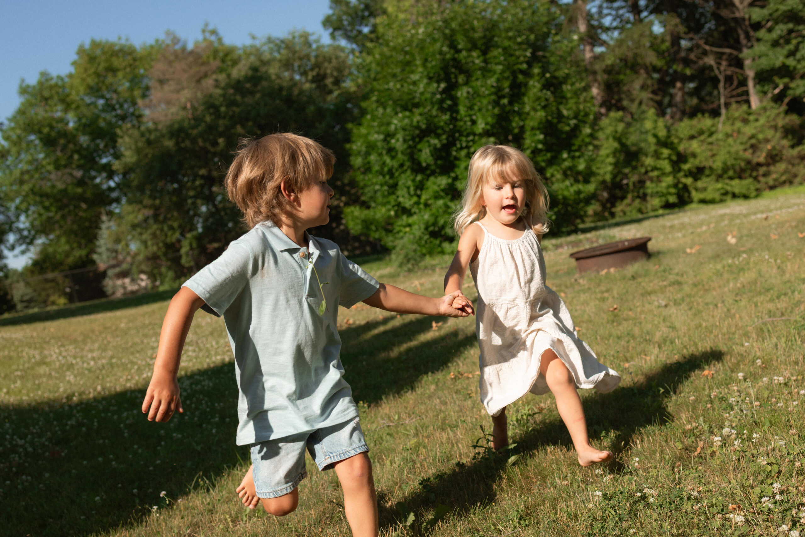 kids running through the yard holding hands during family session 